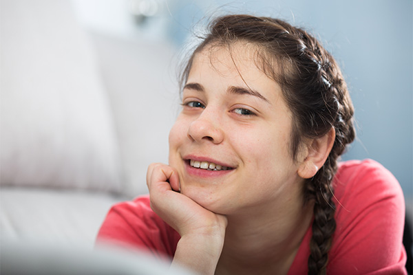 Picture of a young girl with a chin in hand, smiling. 