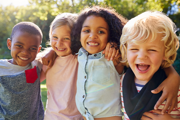 four children standing close together and smiling for the camera