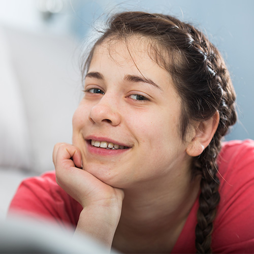 Young girl with her chin in her hand smiling for the camera. 