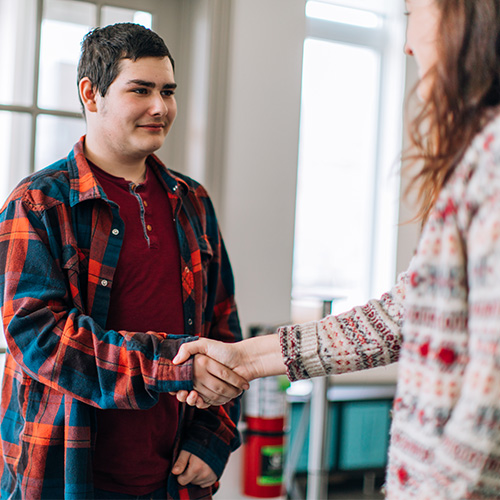 Image of young man shaking mentors hand. 